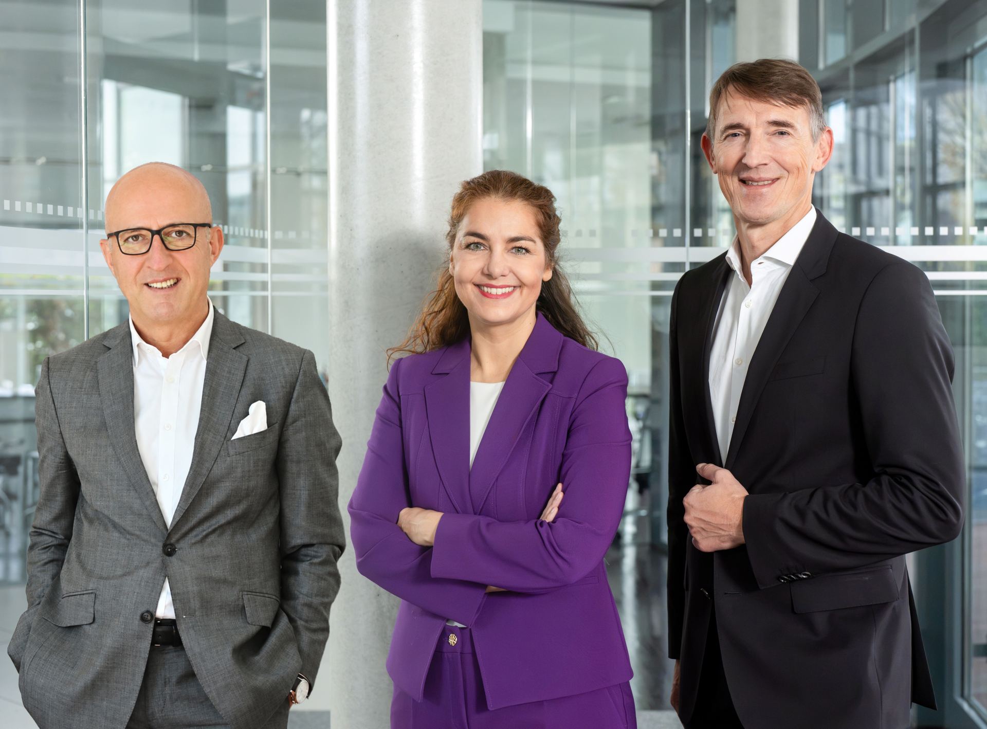 Drei Personen stehen in einem hellen Bürogebäude.